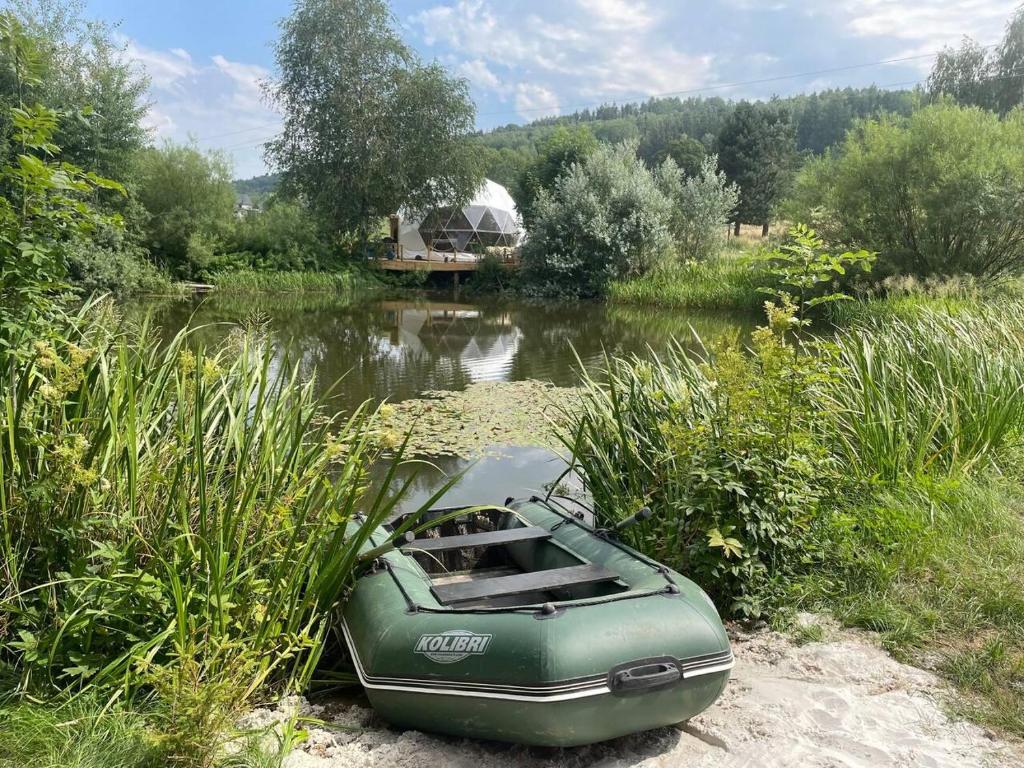 ein grünes Boot auf der Seite eines Flusses in der Unterkunft Glamping Jedlova - Romantic and family getaway in Horní Podluží