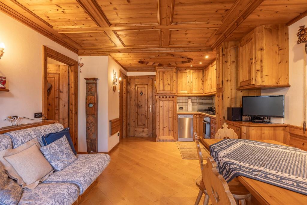 a living room with a couch and a kitchen with wooden cabinets at Casa Lacedel 2, on ski slopes in Cortina dʼAmpezzo