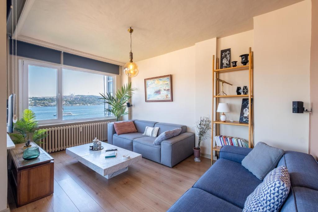 a living room with a blue couch and a large window at Stunning 2Br Apt at the Brim of the Bosphorus in Istanbul
