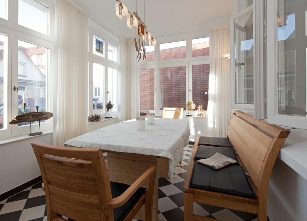 a dining room with a table and chairs and windows at Haus Strandgut in Norderney