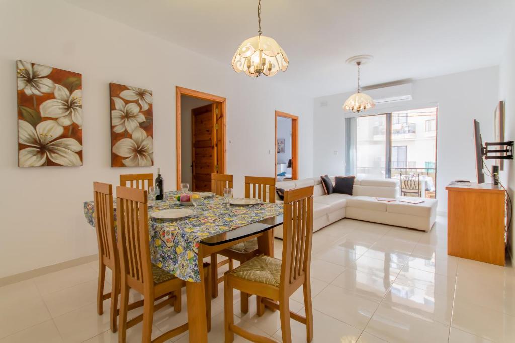 uma sala de jantar e sala de estar com mesa e cadeiras em Cotswold Sea Apart with 3 bdr at Qawra - Happy Rentals em St. Paul's Bay
