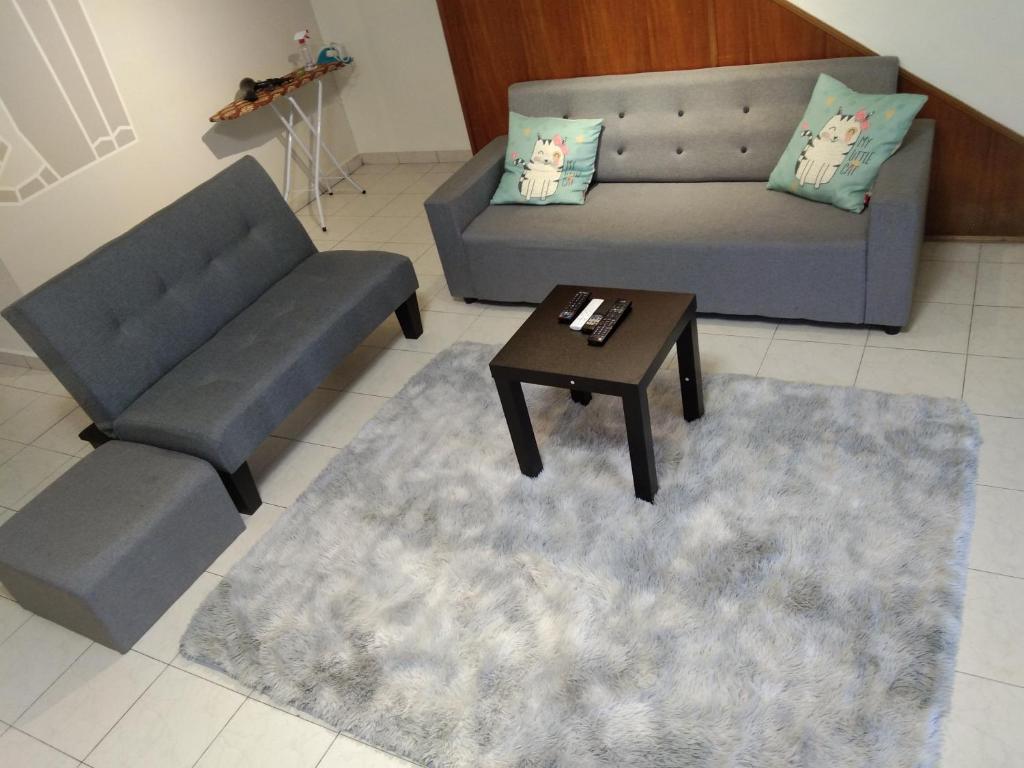 Sala de estar con 2 sofás y mesa de centro en QQ Homestay en Ipoh