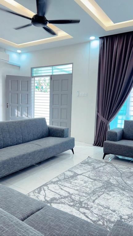 Easy Homestay في Mukah: غرفة معيشة مع أريكة ومروحة سقف