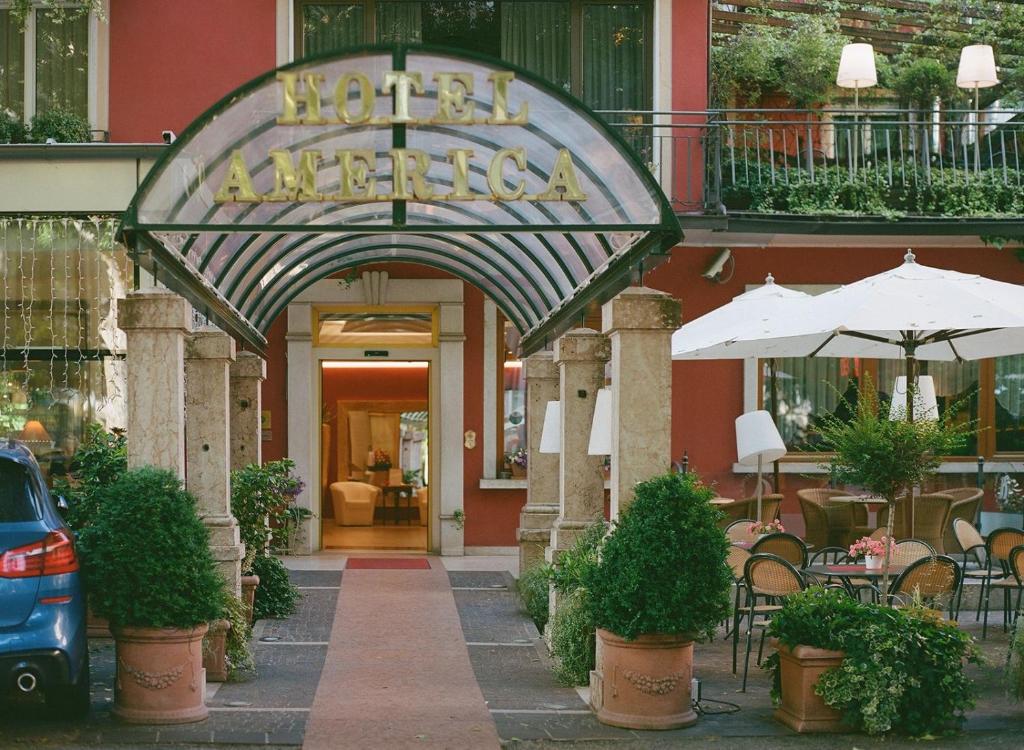 Zugang zu einem Hotel mit einem Tisch und einem Sonnenschirm in der Unterkunft Hotel America in Trient