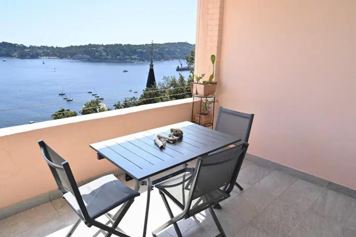une table et des chaises sur un balcon avec vue sur l'eau dans l'établissement Les Lucioles - Vue mer, AC, Wi-Fi, 4 pers, à Villefranche-sur-Mer