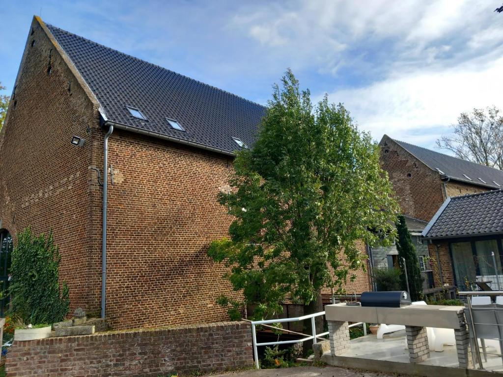 un edificio in mattoni con un albero di fronte di Ruim appartement voor 14 personen a Eijsden