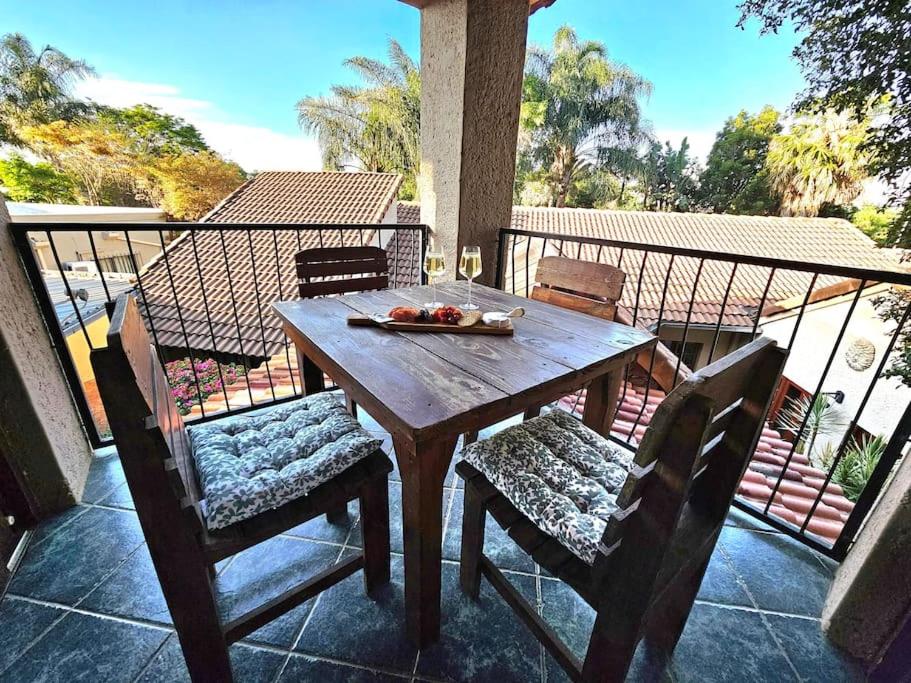 een houten tafel en stoelen op een balkon bij Grobler's Haven Self catering cottage in Pretoria
