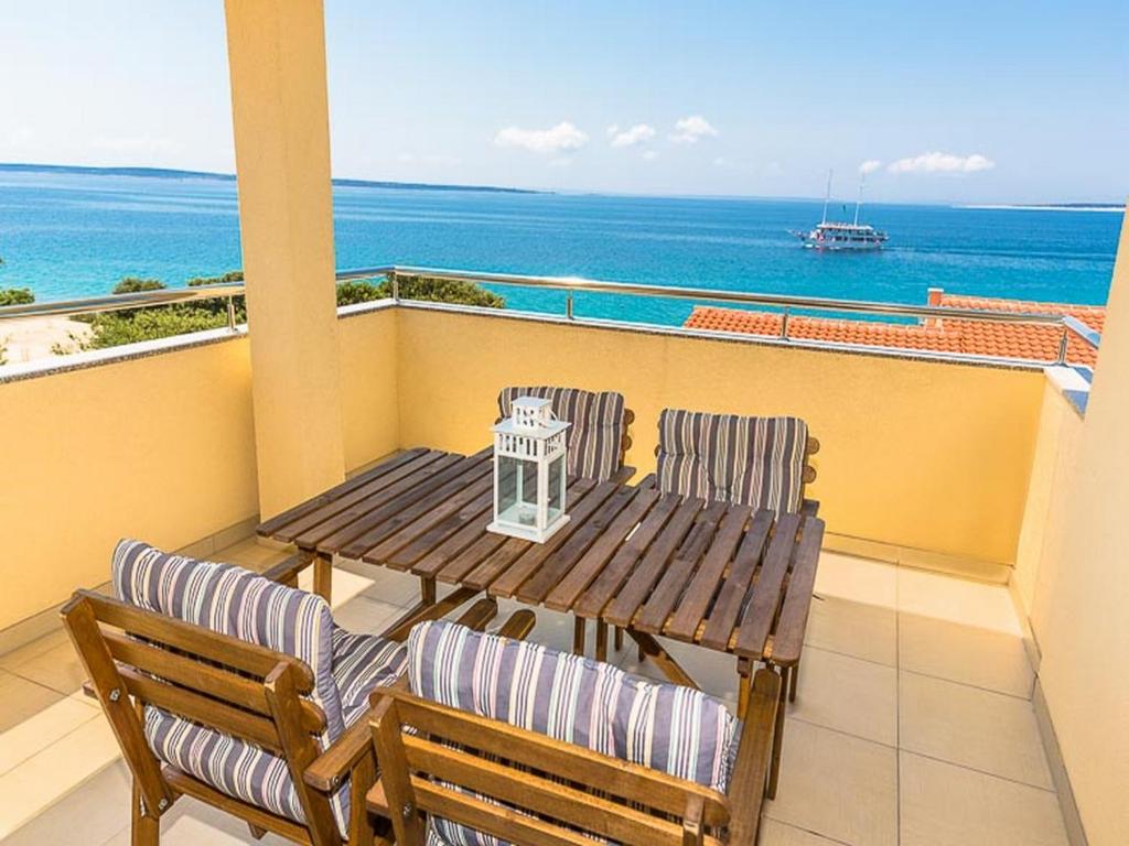 een tafel en stoelen op een balkon met uitzicht op de oceaan bij Apartments Cikač II - modern apartments by the beach in Mandre