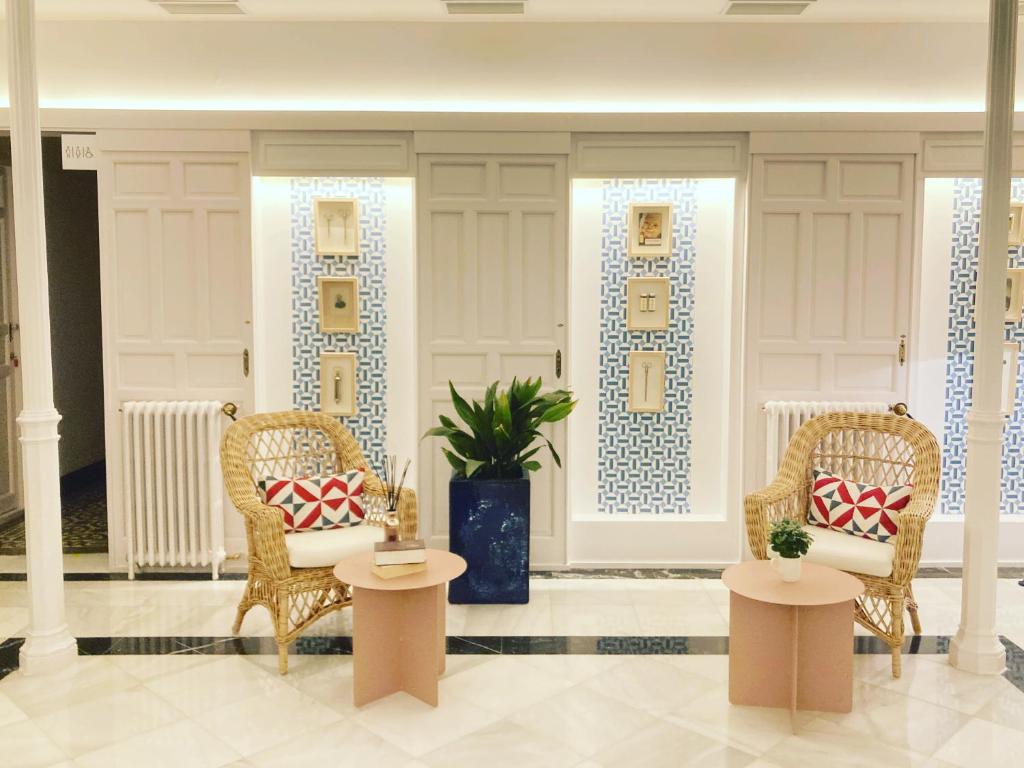 - un hall avec deux chaises en osier et deux tables dans l'établissement Casa del Médico Hotel Boutique, à Alcázar de San Juan