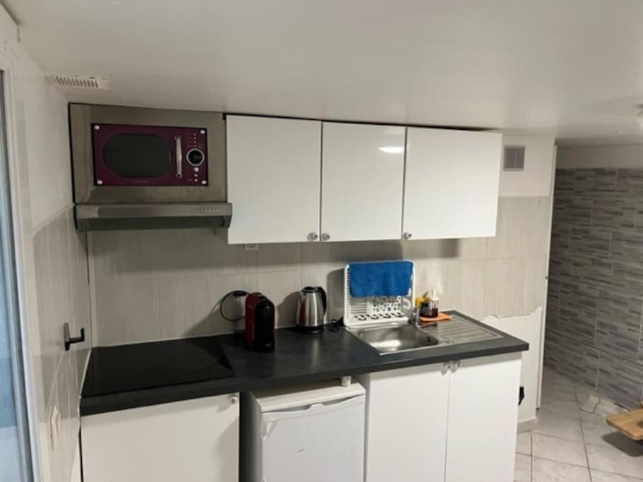 a small kitchen with white cabinets and a microwave at Appartement en plein centre ville du bourget in Le Bourget