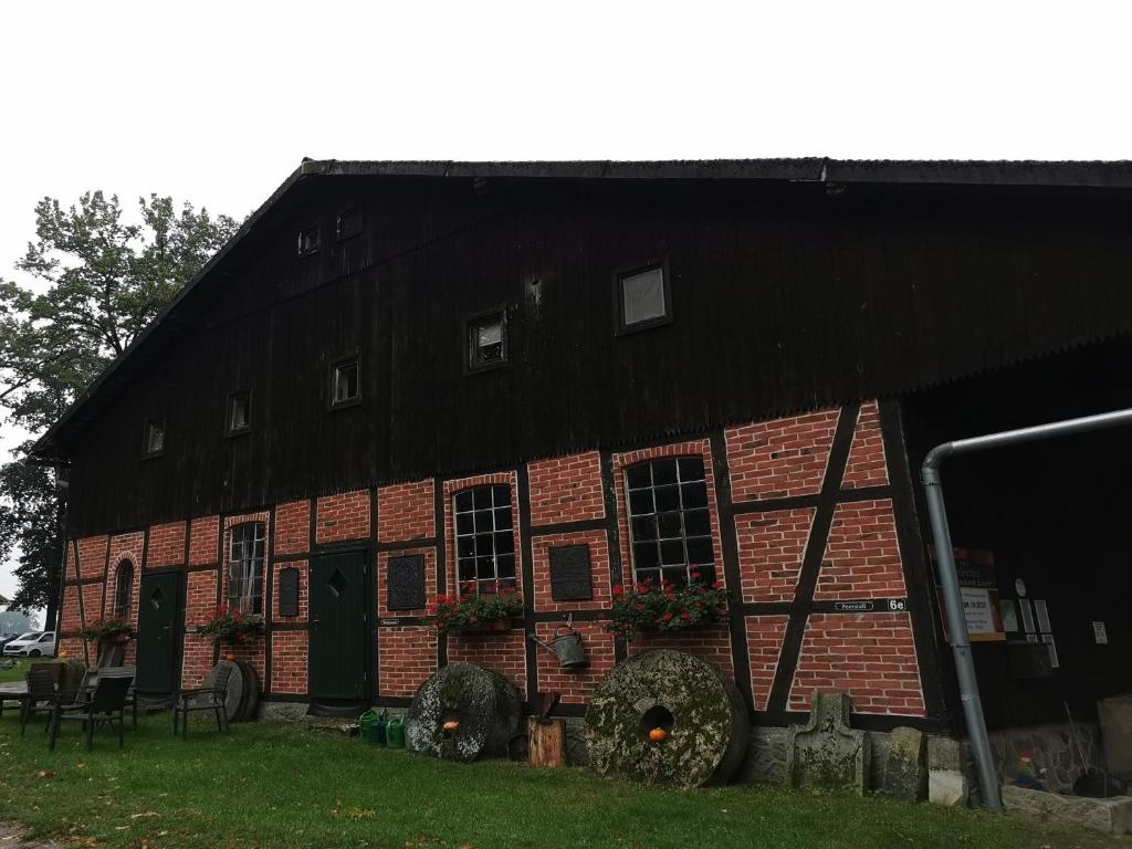 een rode bakstenen schuur met een zwart dak bij Beekenhof Ferienwohnung für Monteure in Bommelsen