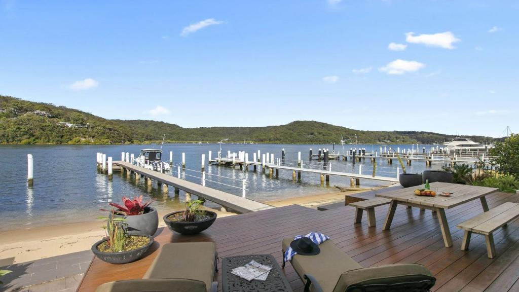 a dock with a table and chairs next to the water at Riptides Booker Bay -Waterfront apartment, walk to shops & cafes in Booker Bay
