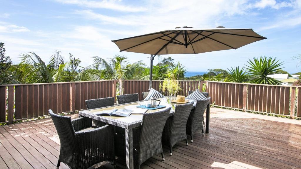 a table and chairs with an umbrella on a deck at A Grand Beach Retreat in Killcare