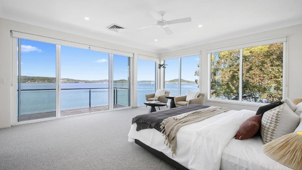 a bedroom with a large bed and large windows at Waters Edge - Point Clare - Pool - Spa - Private Jetty in Point Clare