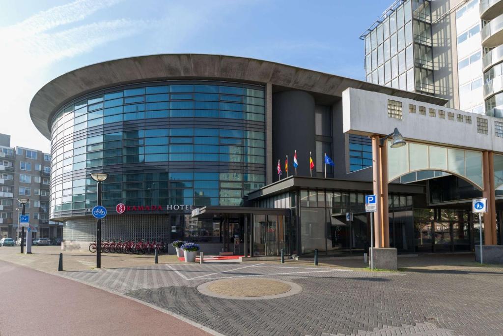 a large glass building in a city at Ramada The Hague Scheveningen in Scheveningen