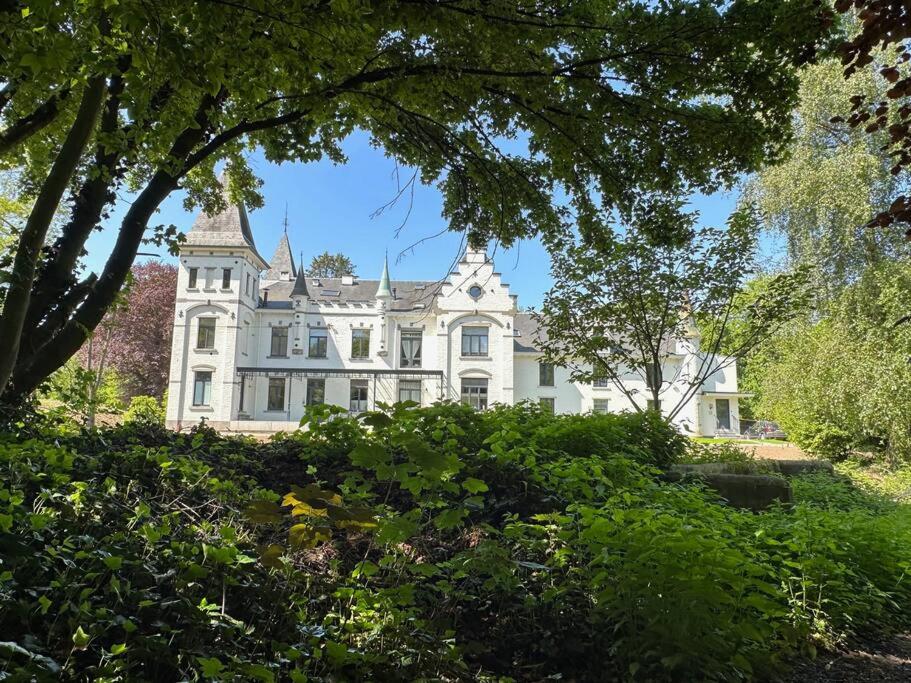 een groot wit huis met bomen ervoor bij Vakantiewoning Hoogveld in Kortessem