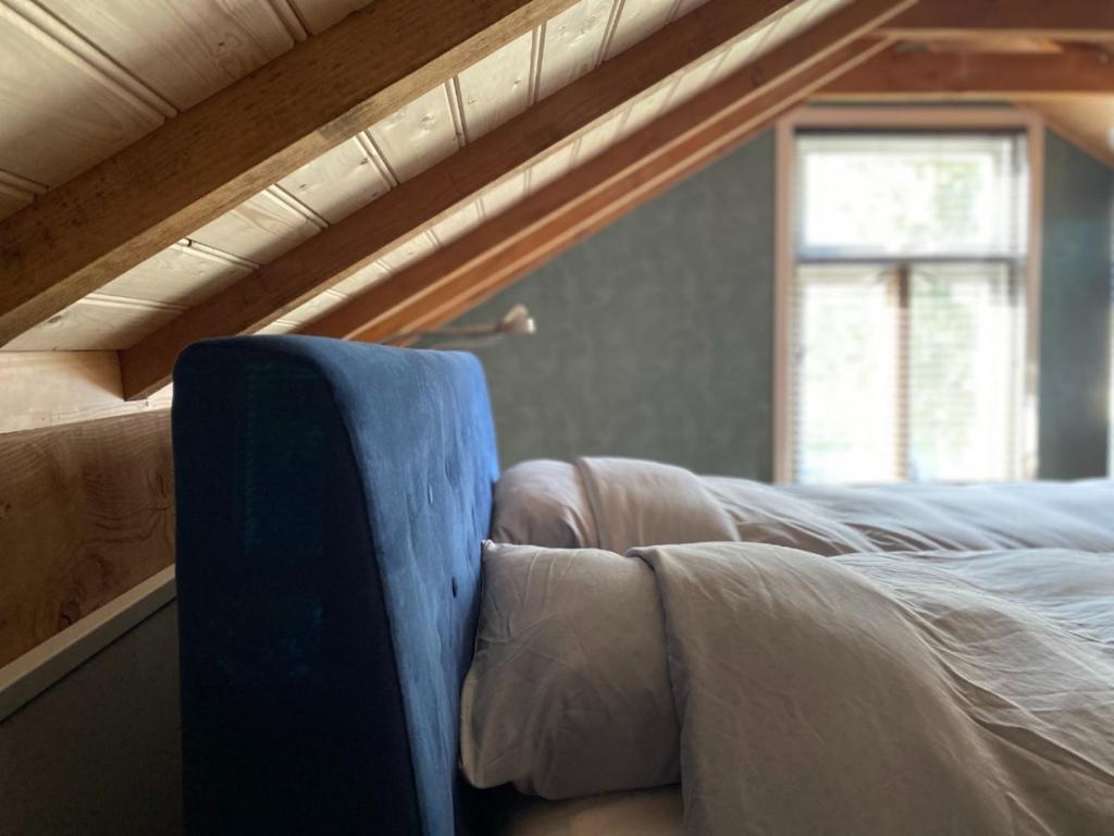 een bed met een blauwe stoel in een kamer bij Brour&Bos in Laren
