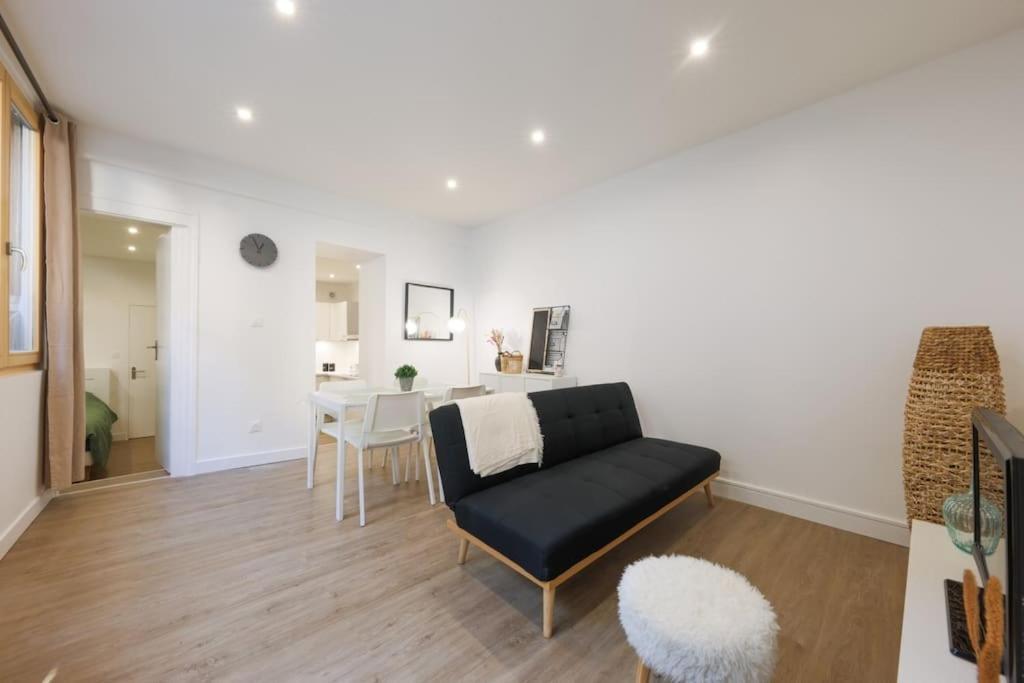 un salon avec un canapé noir et une table dans l'établissement Le Nid Alsacien - Charmant T2 au centre ville de Strasbourg, à Strasbourg