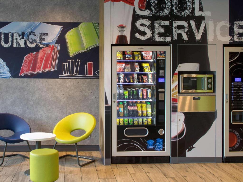 a soda vending machine in a store with a yellow chair at ibis budget Montceau les Mines in Montceau-les-Mines