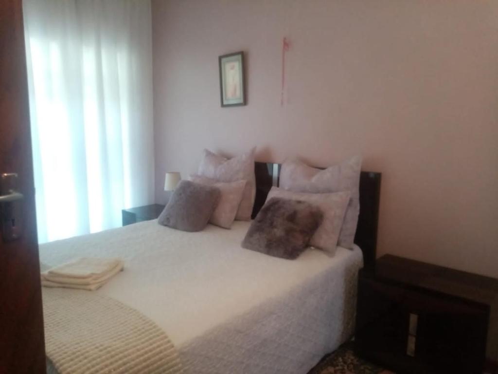 um quarto com uma cama com lençóis brancos e almofadas em Hilltop town view em Klerksdorp