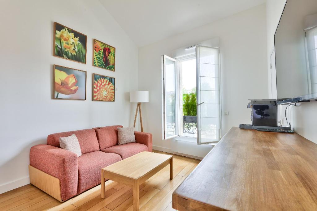 a living room with a pink couch and a table at Charmant appartement à 10 minutes de la Défense in Suresnes