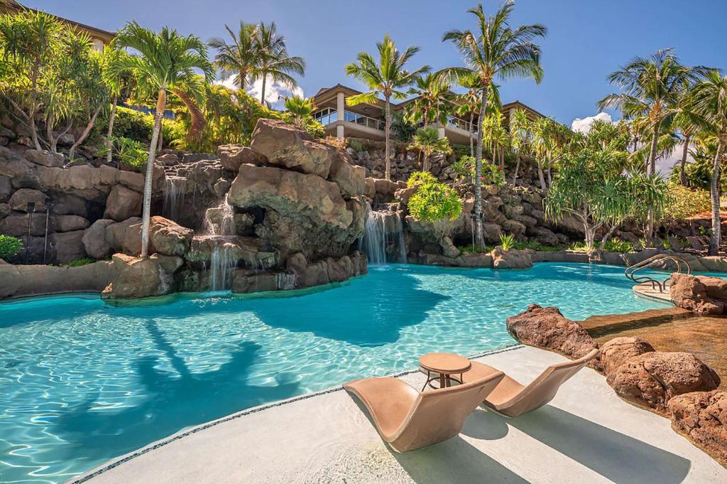 a swimming pool with a waterfall in a resort at Ho Olei Residences - CoralTree Residence Collection in Wailea