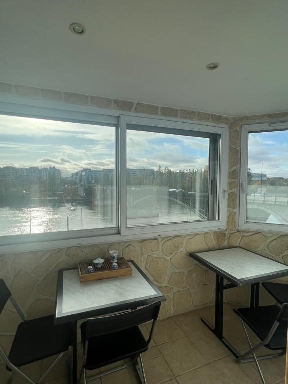 a room with two tables and two windows with a view at Courbevoie Riverview in Courbevoie