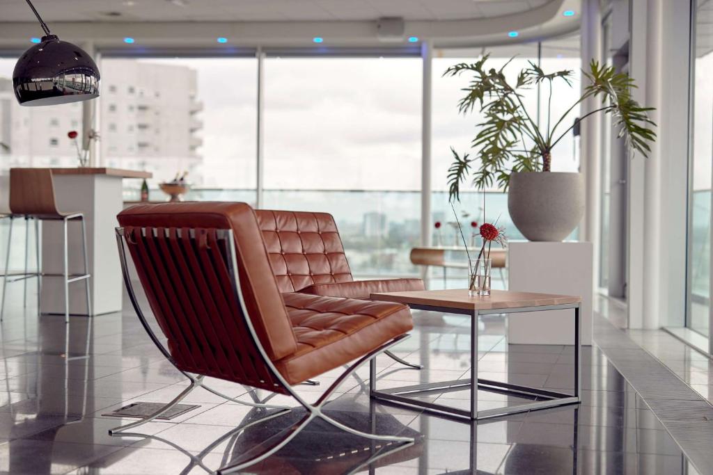 a living room with a leather chair and a table at Maashotel Rotterdam Centre in Rotterdam