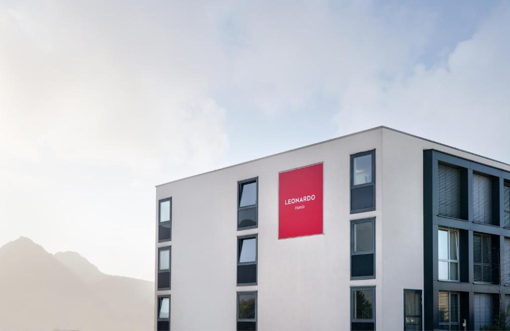 a white building with a red sign on it at Leonardo Hotel Salzburg Airport in Salzburg