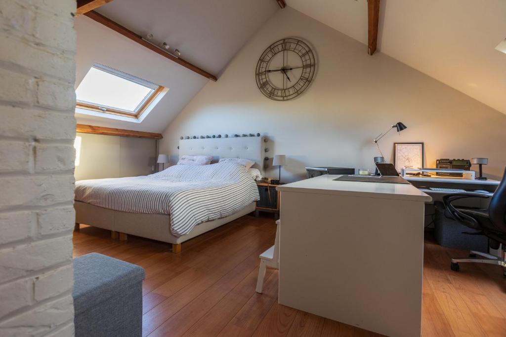 um quarto com uma cama e um relógio na parede em Chez LyLy em Wavre
