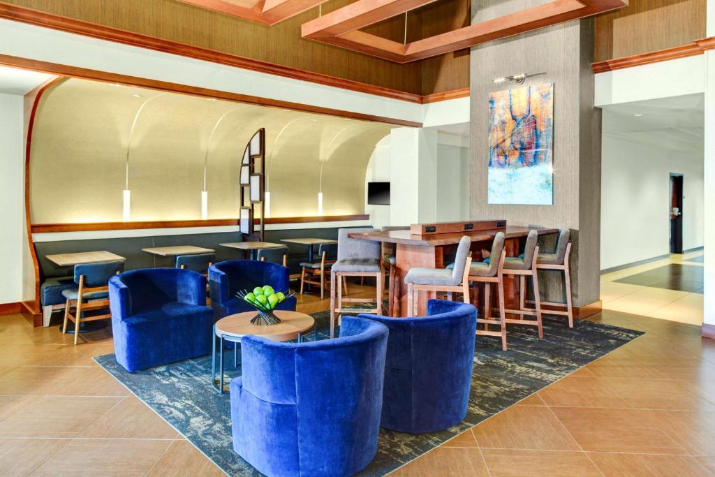 a lobby of a hotel with blue chairs and tables at Oklahoma City Airport Hotel & Suites Meridian Ave in Oklahoma City