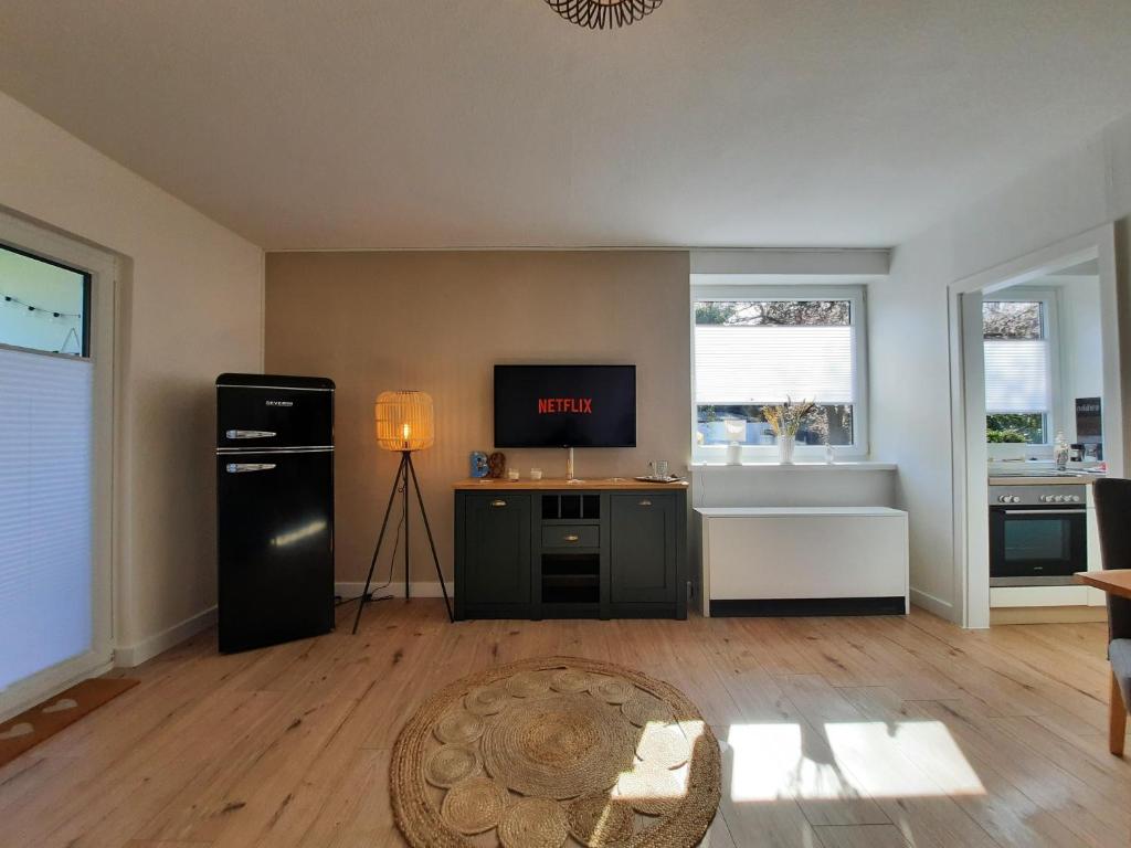 a living room with a black refrigerator and a tv at Träumeria in Butjadingen