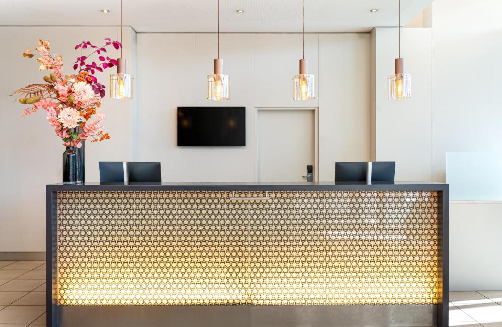 a lobby with a reception desk with a vase of flowers at Leonardo Hotel Salzburg Airport in Salzburg
