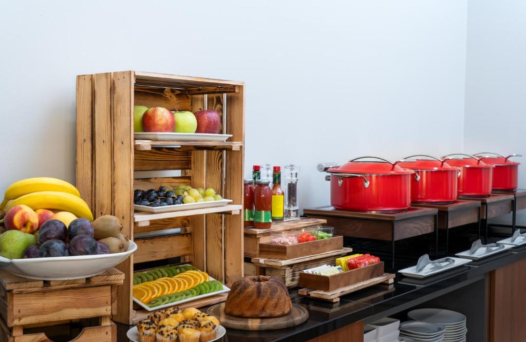 a buffet with fruits and vegetables and pots and pans at Leonardo Hotel Salzburg Airport in Salzburg