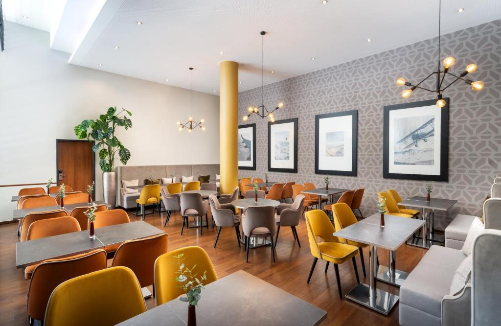 a dining room with tables and yellow chairs at Leonardo Hotel Salzburg Airport in Salzburg