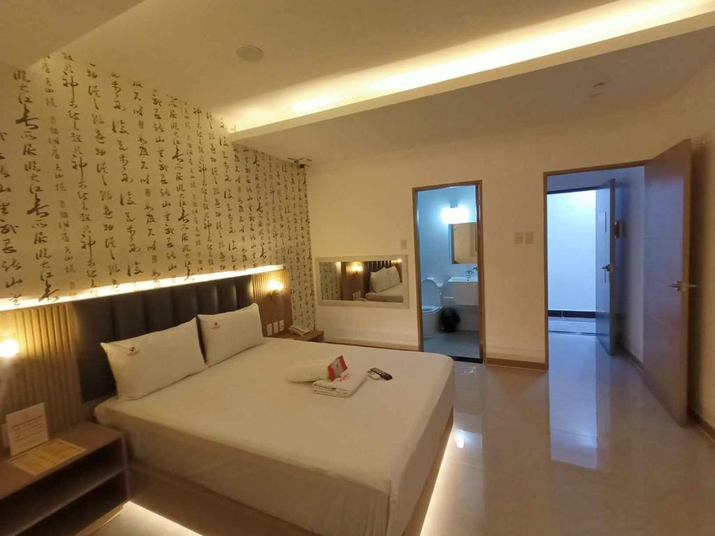 een slaapkamer met een groot wit bed en een badkamer bij Honey Hotel - Balibago in Angeles