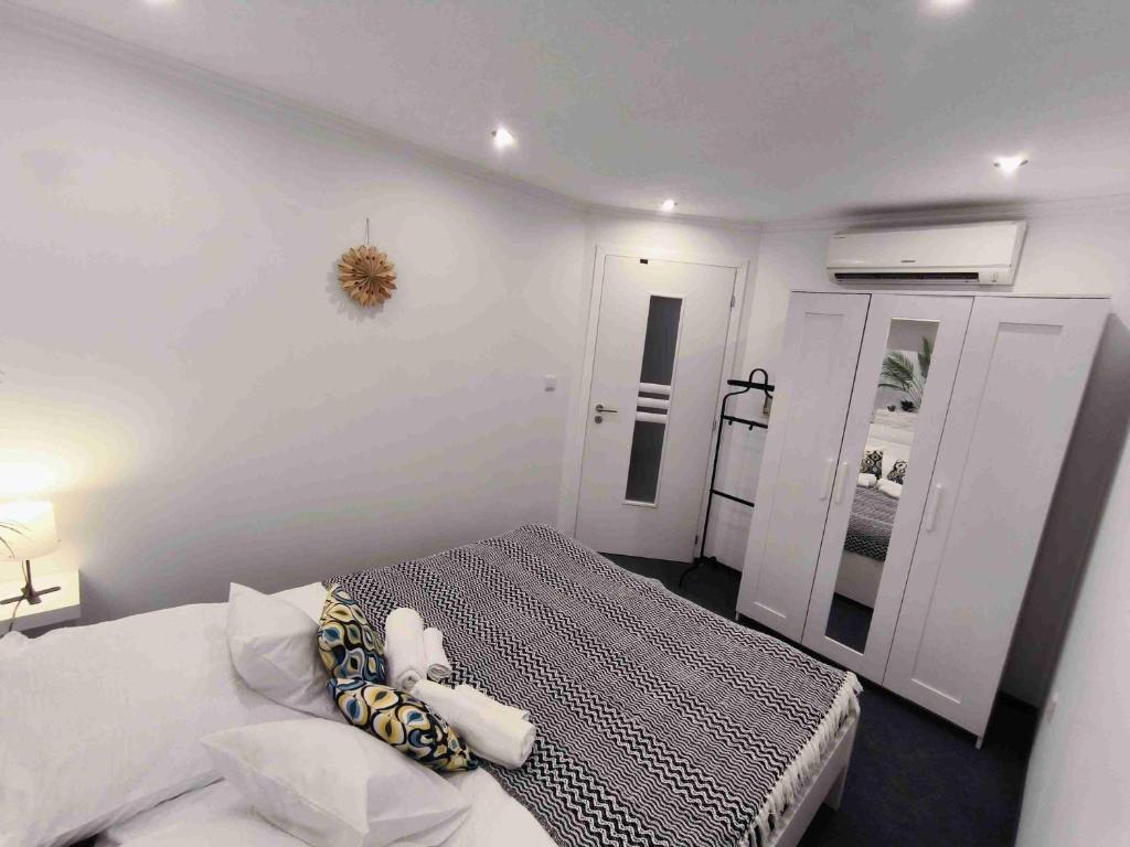 a white bedroom with a bed and a mirror at Baky House in Balatonlelle