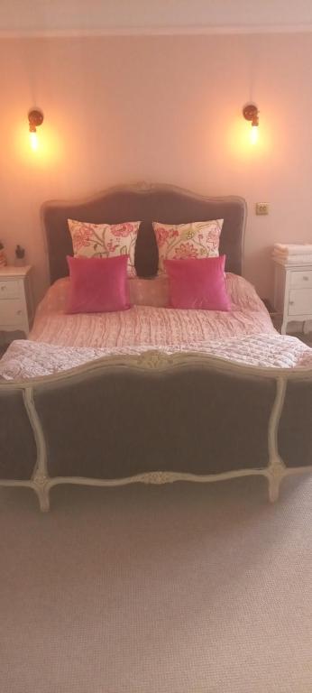 a bedroom with a large bed with pink pillows at Beautiful self-contained annex in Hoylake