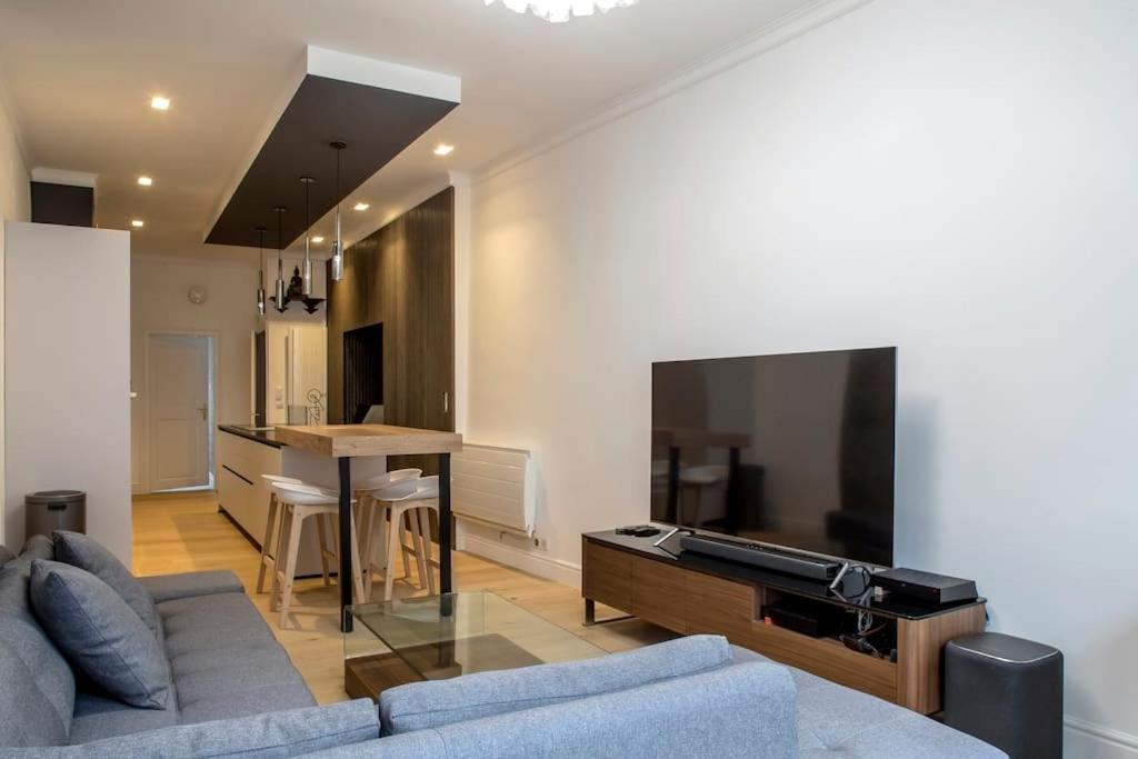 un salon avec un canapé et une télévision à écran plat dans l'établissement Le Carré D'or - Près de la place Gutenberg, à Strasbourg