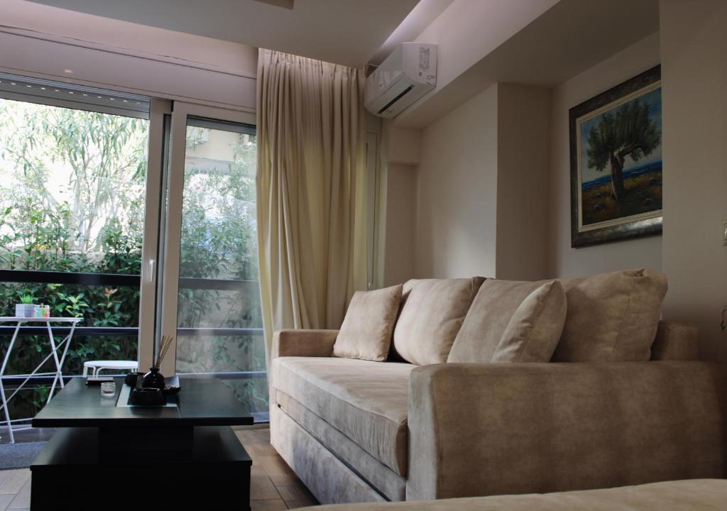 a living room with a couch and a large window at The Ellinikon - Metro Apartment in Athens