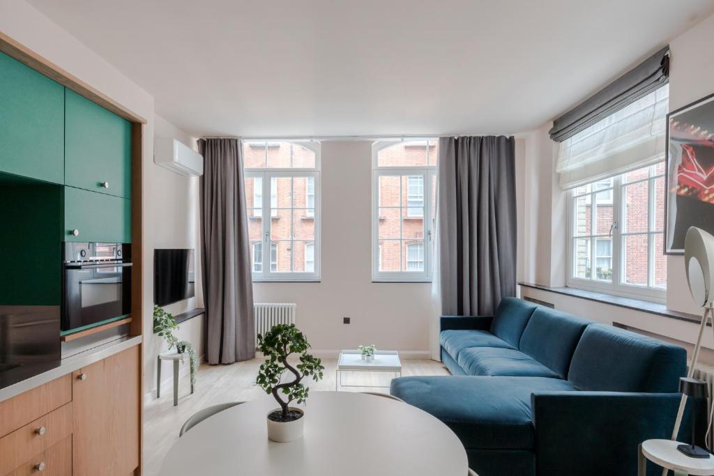 een woonkamer met een blauwe bank en een tv bij Casa Camisa - Soho - by Frankie Says in Londen