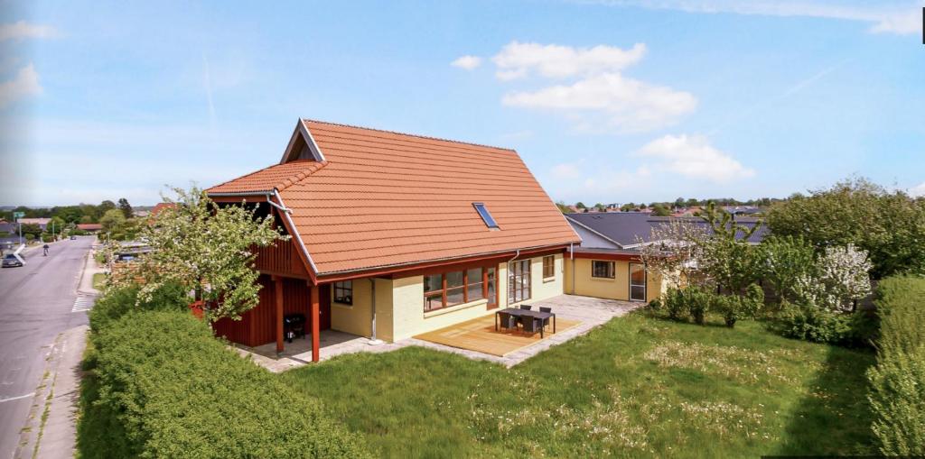 una pequeña casa amarilla con techo rojo en 4 bedroom 200m2 luxury house with garden in Horsens, en Horsens