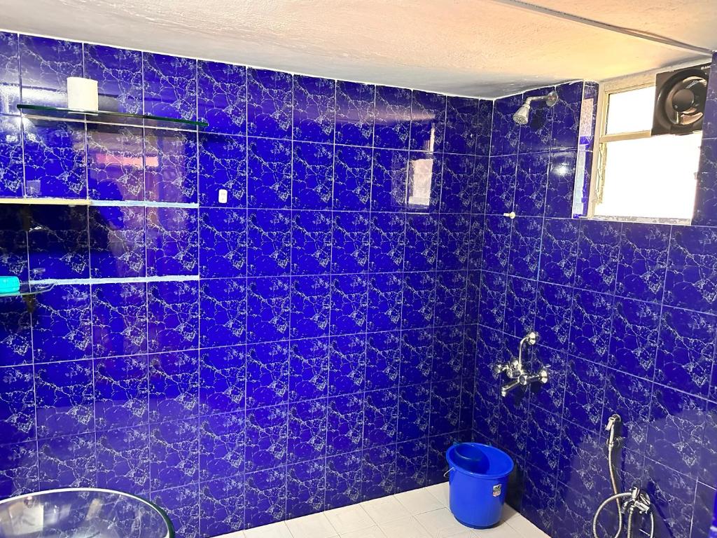 a bathroom with a purple tiled wall with a shower at James Guesthouse in Bogmalo