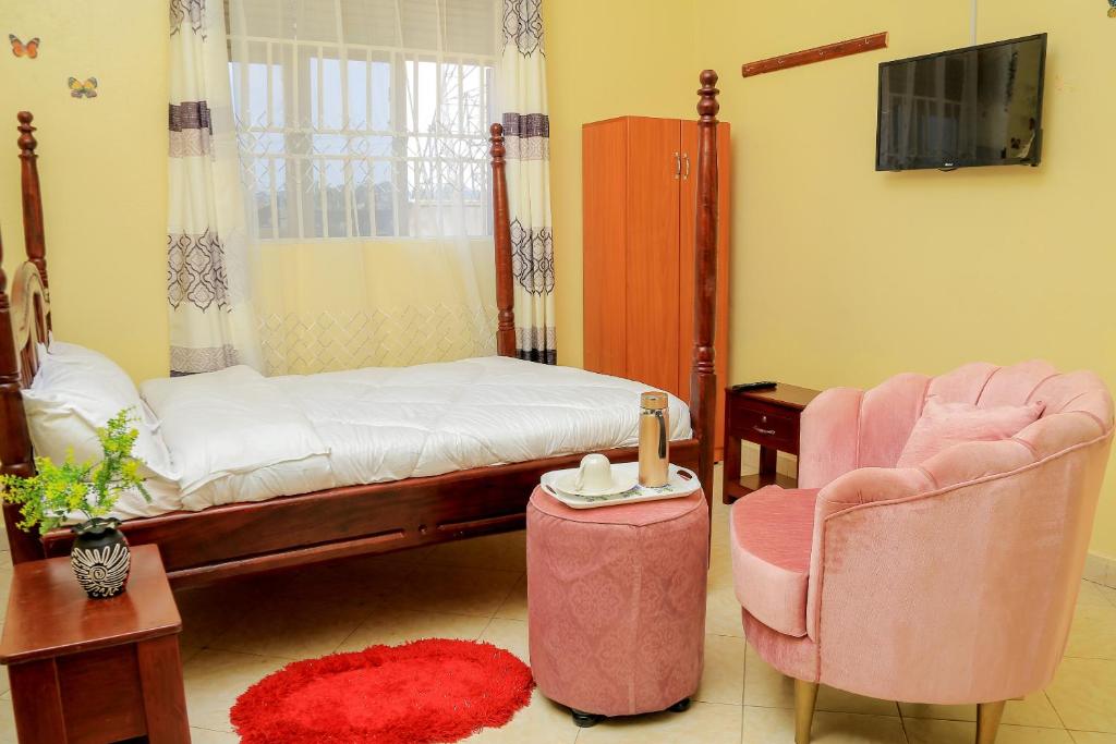 a bedroom with a bed and two chairs and a tv at Exotic Inn and Apartments in Kampala