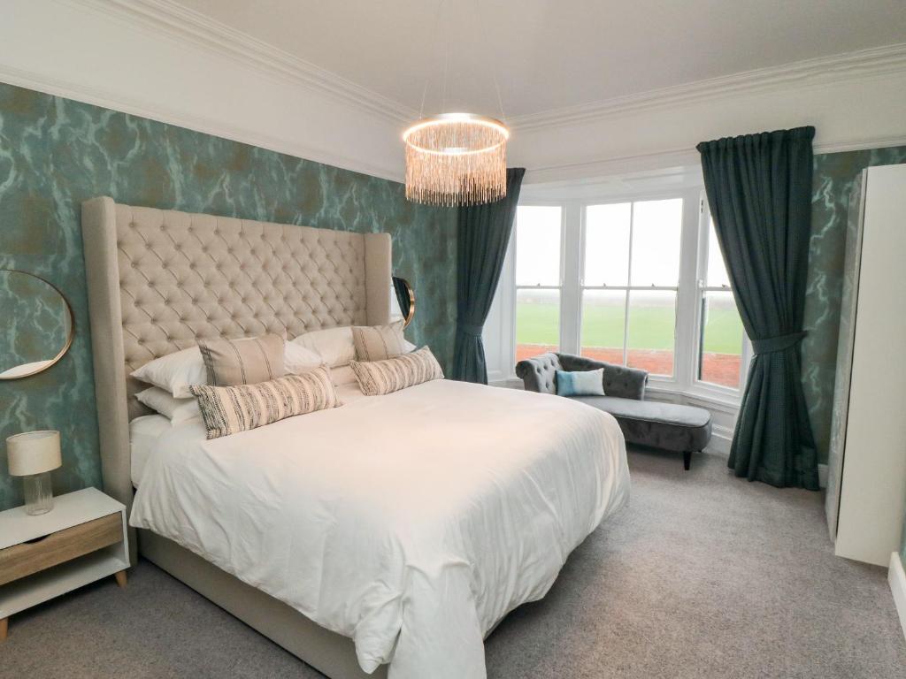 um quarto com uma grande cama branca e um lustre em No 20 The Headland em Hartlepool