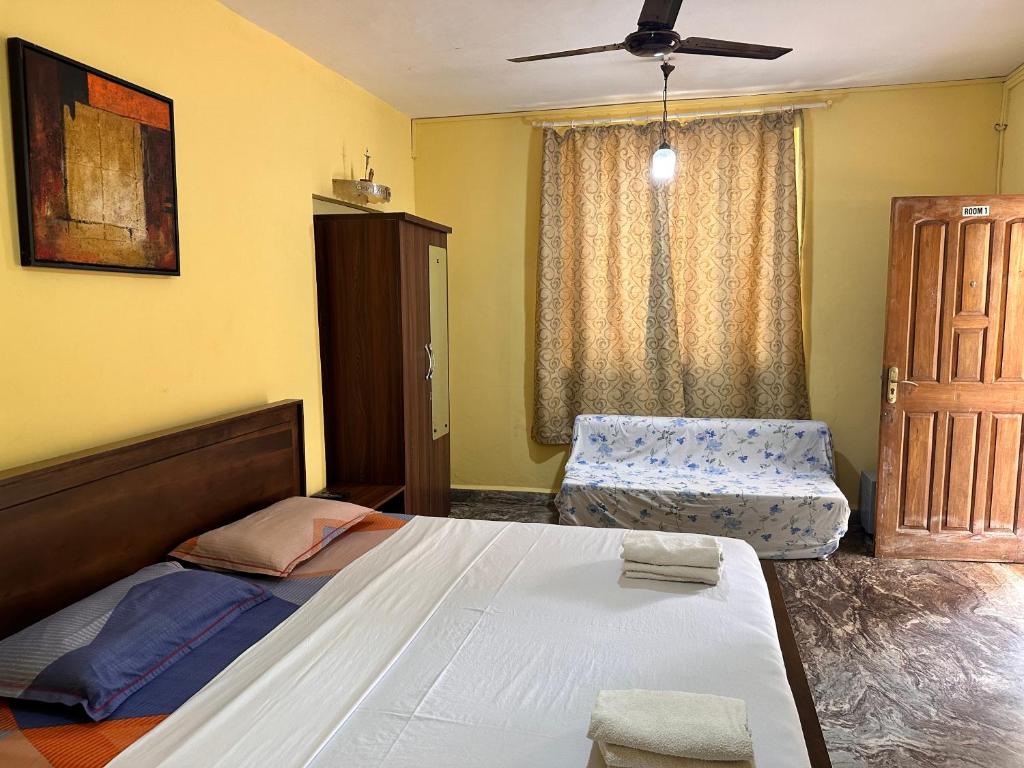 a bedroom with a large bed and a chair at James Guesthouse in Bogmalo