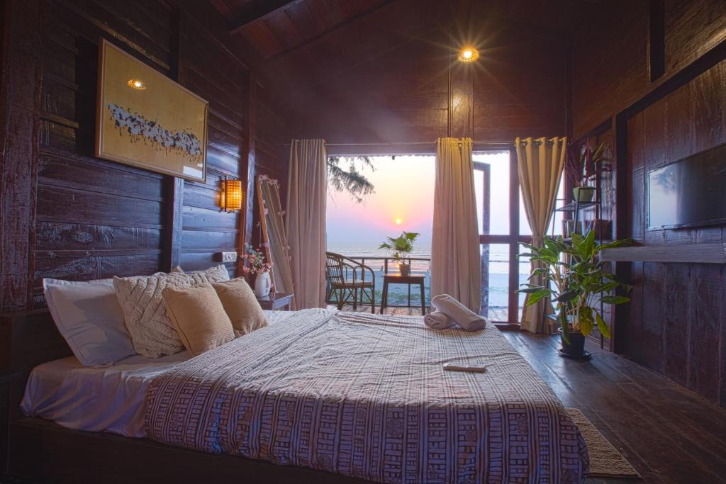 a bedroom with a bed with a view of the ocean at Woodpegger By The Beach, Mandrem in Mandrem