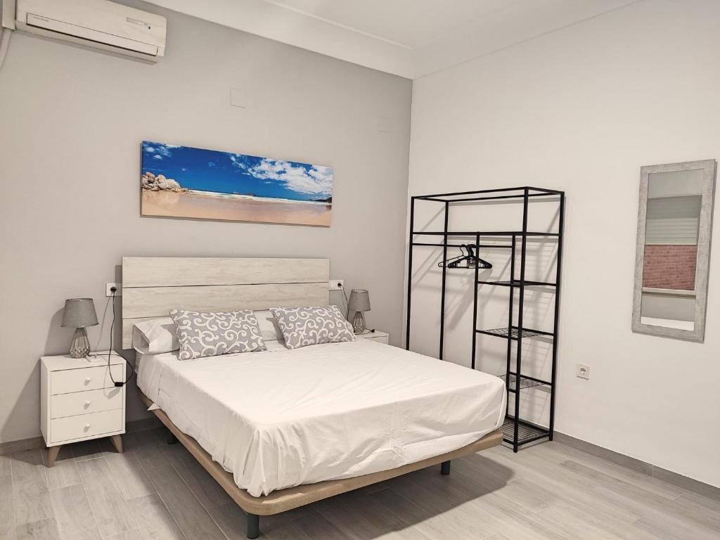 a white bedroom with a bed and a shelf at Alojamientos IMEH y Cordoban in Córdoba
