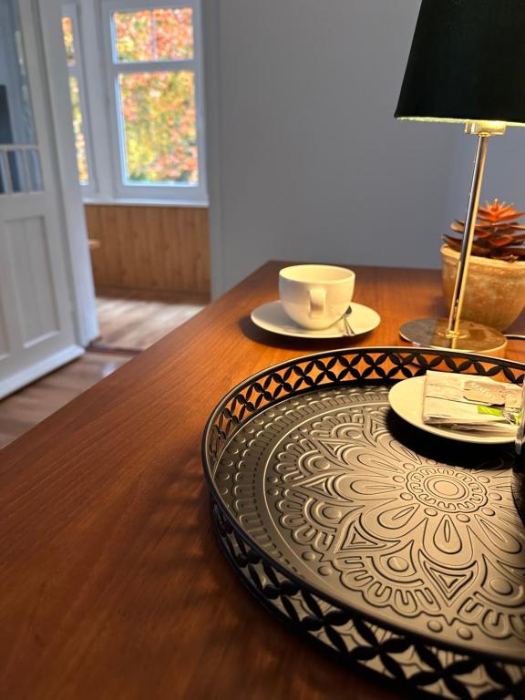 a wooden table with two plates and a lamp on it at Willa pod Bukami in Polanica-Zdrój