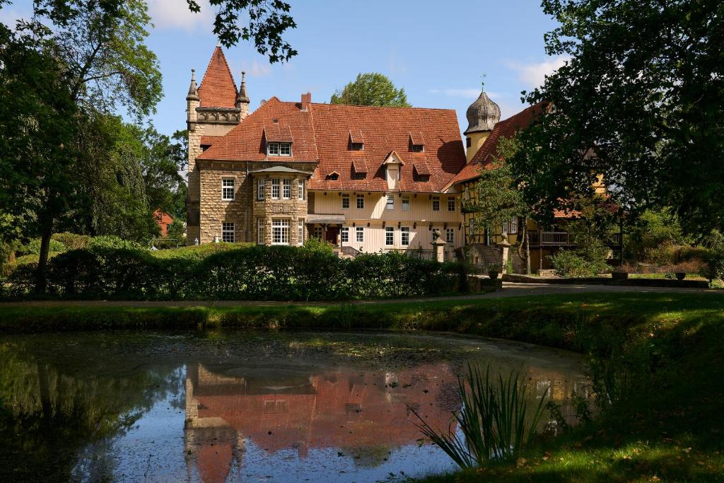 una casa grande con un estanque frente a ella en Schloss Rössing - Messezimmer in historischem Ambiente, en Nordstemmen
